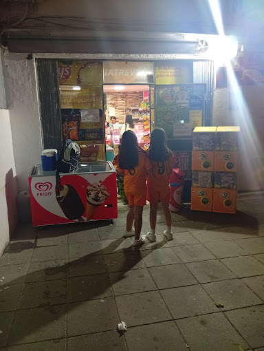 Façade de la boutique la nuit avec des clients qui entrent, ouverte jusqu'à 23h30